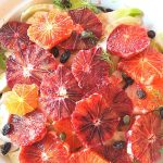 A salad plate with sliced blood oranges over sliced fennel with some capers and raisins tossed in.