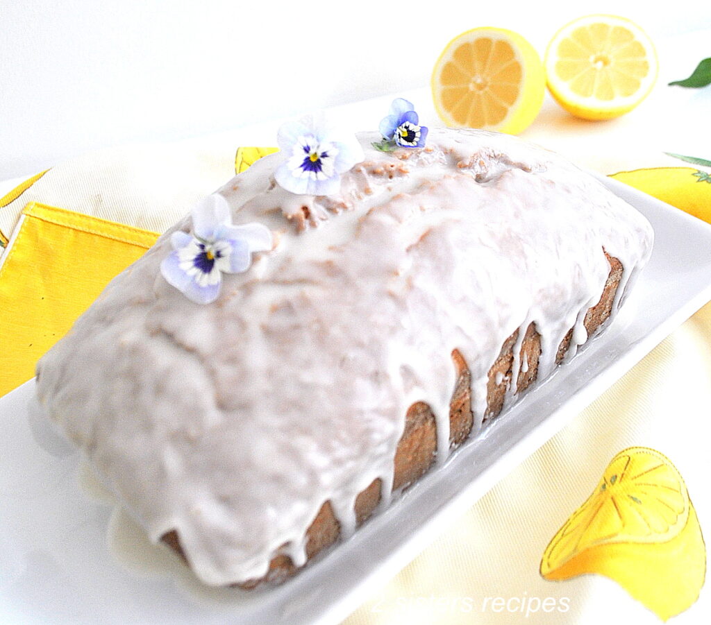 A load of lemon zucchini bread topped with a glaze served on a white platter.