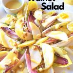 A platter filled with endive leaves, sliced pears, celery, chopped walnuts and dressing on the side.