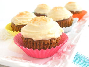 5 cupcakes topped with icing in colorful paper liners on a white platter.