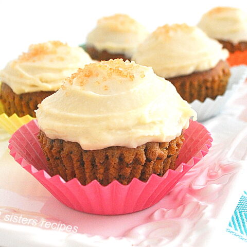 5 cupcakes topped with icing in colorful paper liners on a white platter.