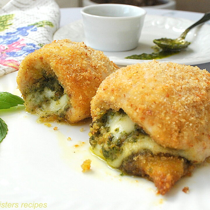 A chicken rollatini's stuffed with pesto and cheese served on a white dinner plate.