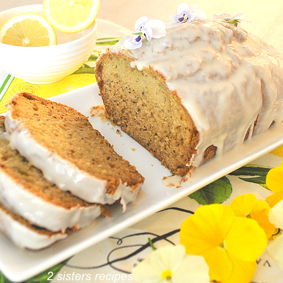 A white serving platter with a quick bread sliced with white icing on top.