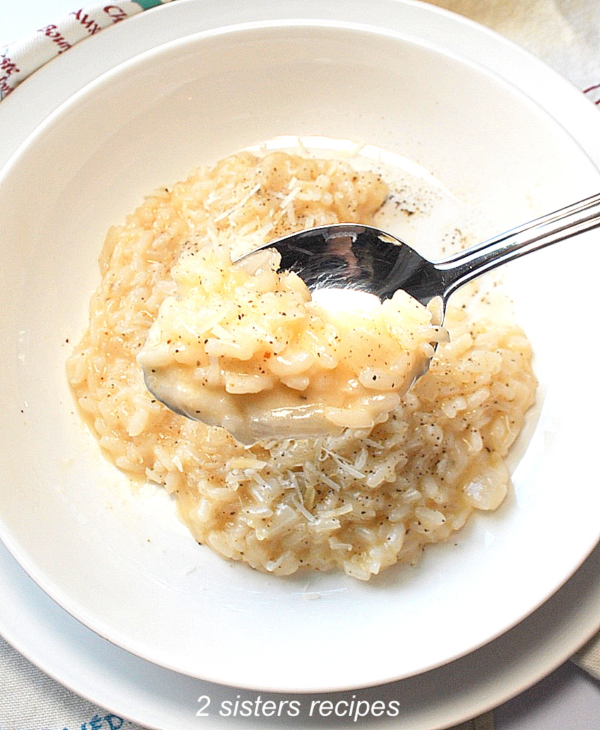 A spoonful of risotto with cheese and black pepper served in white plate.