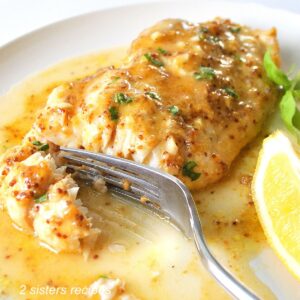 A serving of white fish with a mustard glaze and a fork sliced into it.