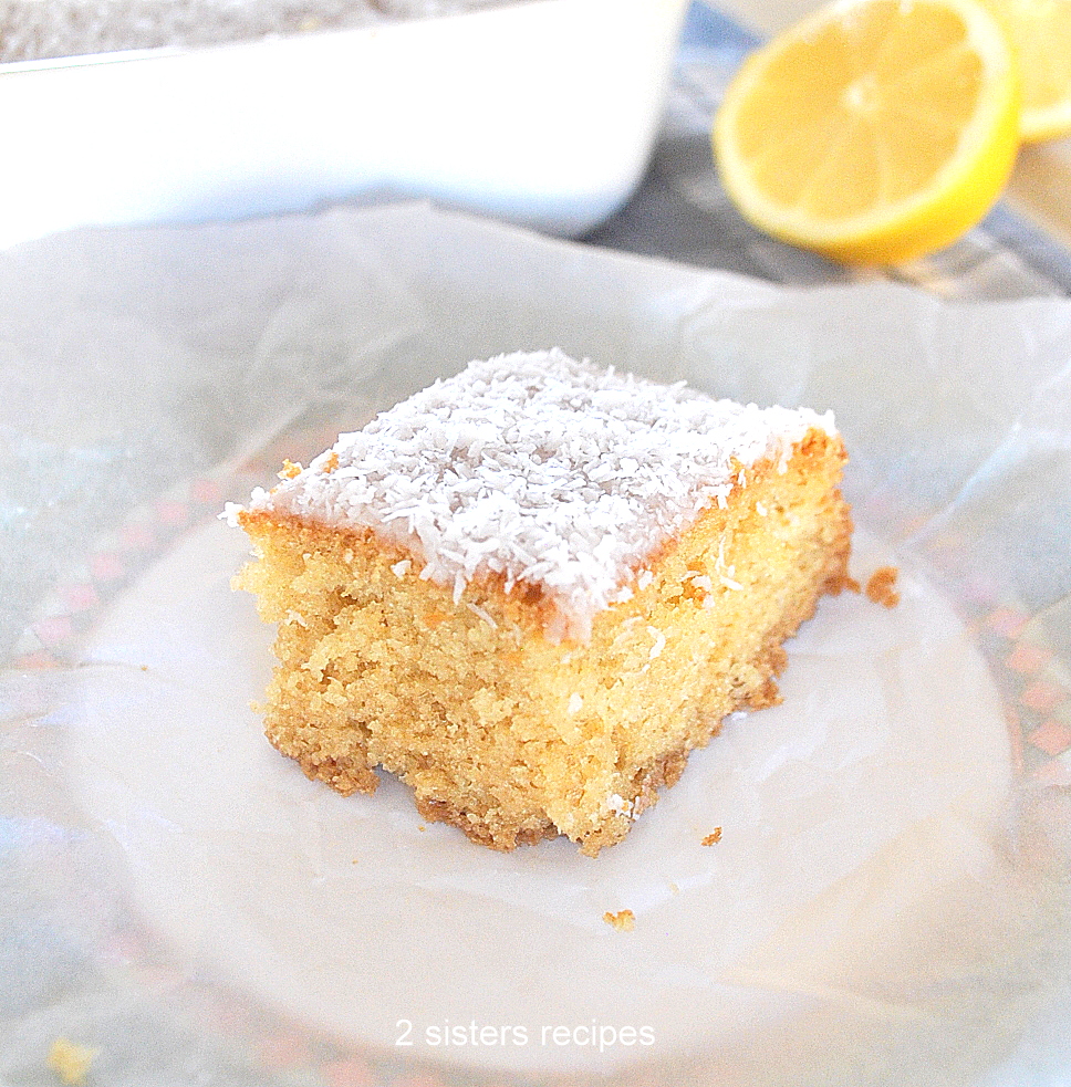 A slice of lemon cake with coconut glaze on top, serve on a white plate.