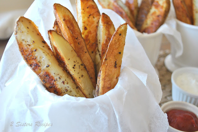 A cup with parchment paper filled with steak fries.