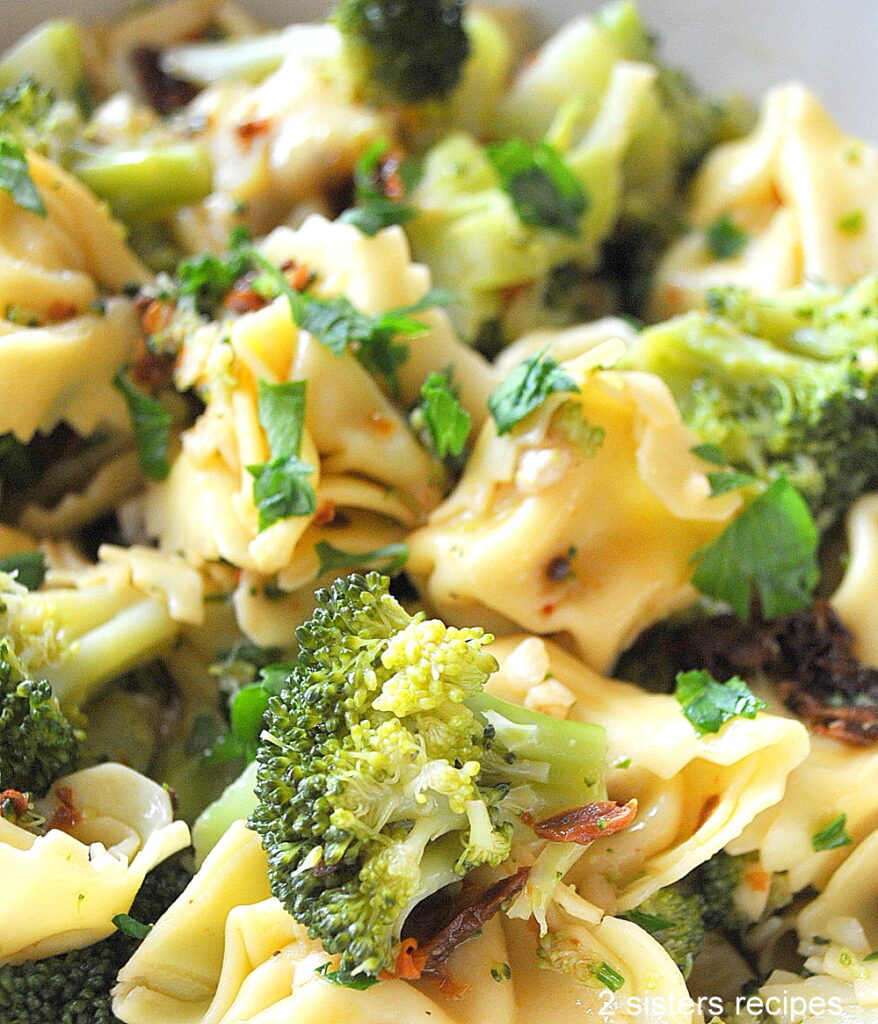 Tossed together are cooked pasta with florets of broccoli, sundried tomatoes, and chopped parsley.