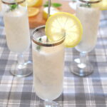 Three fluted glasses filled with a white cold lemon sorbet, with a lemon slice on the rim of the glasses and mint on top.