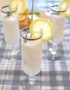 Three fluted glasses filled with a white cold lemon sorbet, with a lemon slice on the rim of the glasses and mint on top.