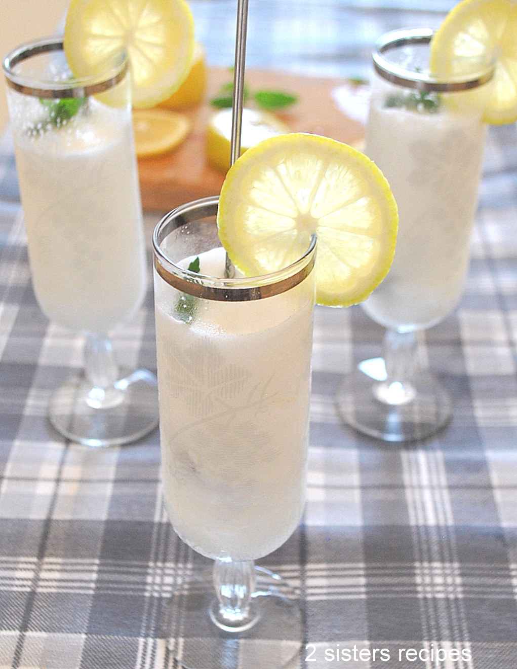 Three fluted glasses filled with a white cold lemon sorbet, with a lemon slice on the rim of the glasses and mint on top.