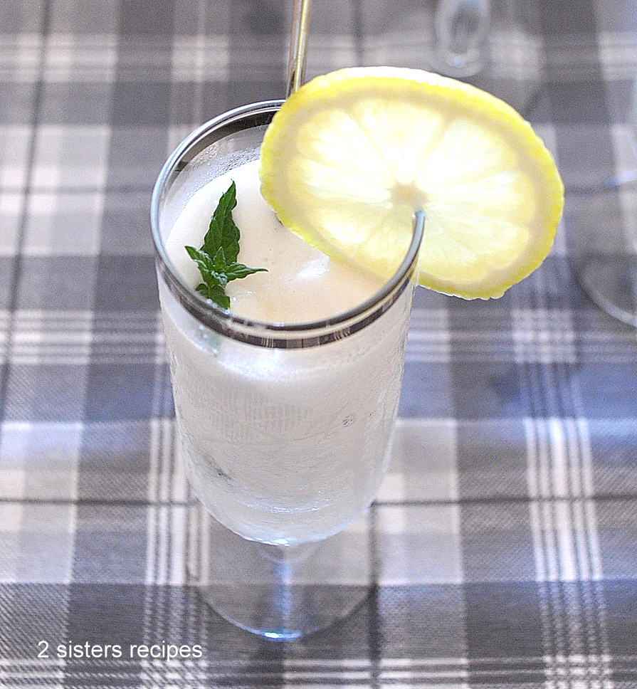 A tall fluted glass filled with lemon sorbet and garnished with a slice of lemon and mint leaf.