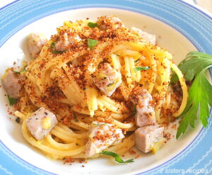 A blue and white dish with a serving of spaghetti with cubes of fresh tuna, topped with crispy bread crumbs.