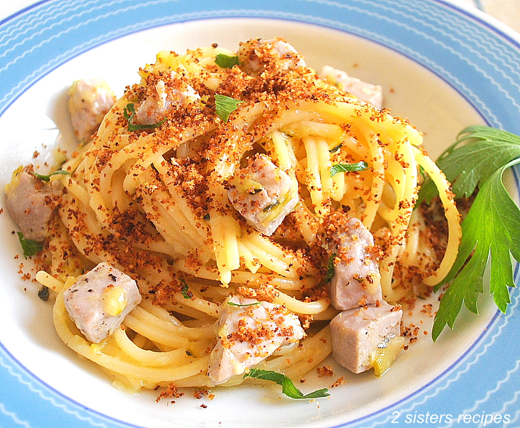 A blue and white dish with a serving of spaghetti with cubes of fresh tuna, topped with crispy bread crumbs.