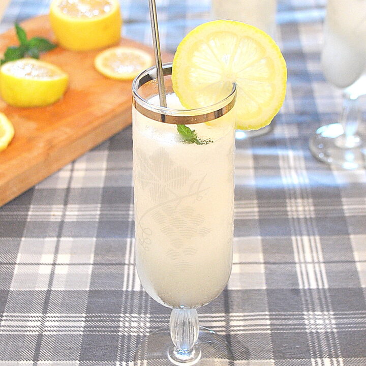 A tall fluted glass filled with a white sorbet, topped with a lemon slice and mint leaf, with a wood cutting board with slices of lemon next to it.