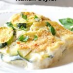 A white plate with a serving of creamy potato and zucchini au gratin.