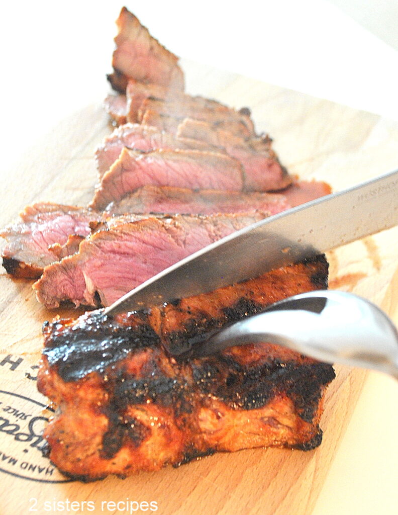 Slicing the New York Strip steak on a wood board.