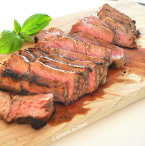 A cutting board filled with a steak thinly sliced.