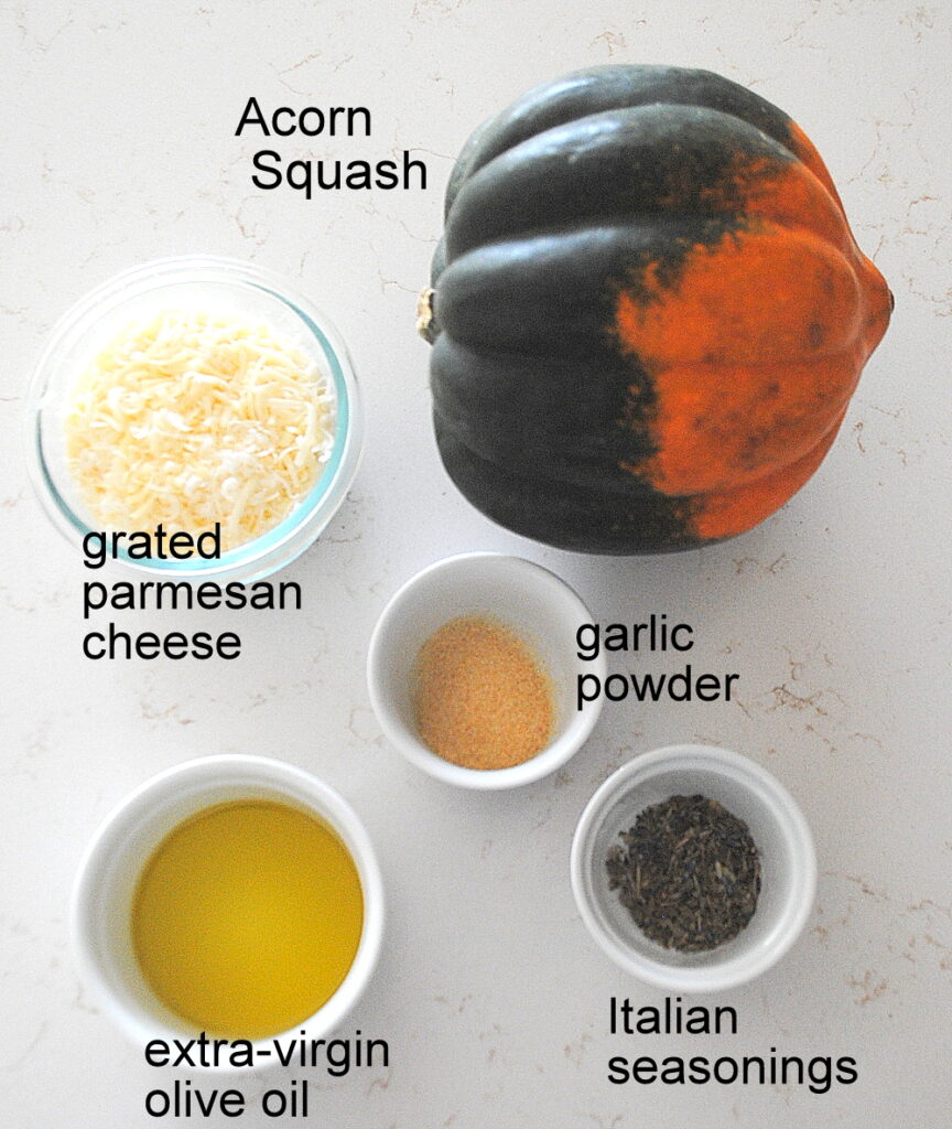On the counter is a acorn squash, along with small bowls filled with grated cheese, olive oil, herbs and garlic powder.