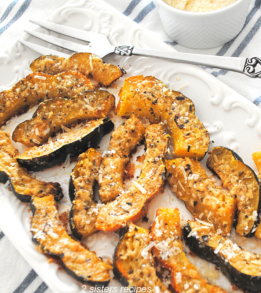 White platter filled with slices of baked acorn squash topped with parmesan-herb crust.