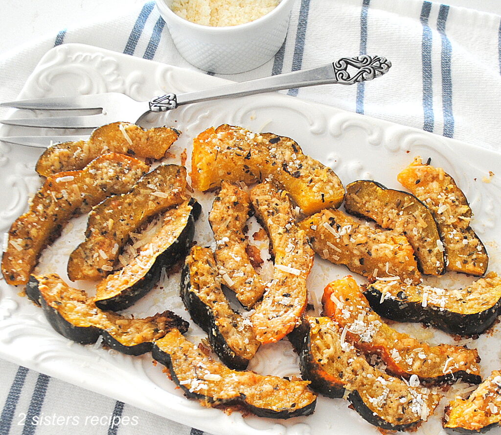 A white platter filled with slices of acorn squash baked with parmesan coating.