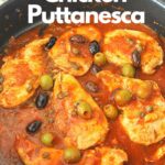 A bllack skillet filled with cooked chicken breasts smothered in puttanesca sauce.