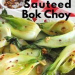 Sautéed bok choy is served on a white platter with red pepper flakes scattered on top.