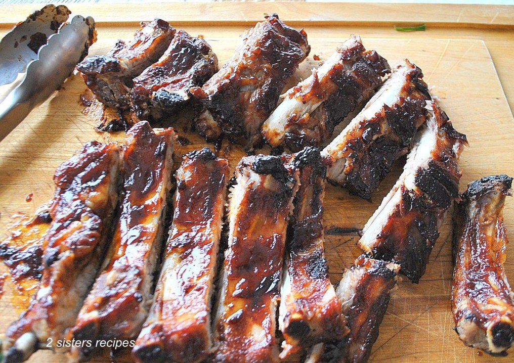 A wood cutting board with sliced roasted baby back ribs.