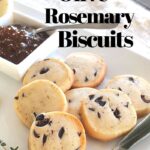 A white plate filled with shortbread biscuits studded with black olives.