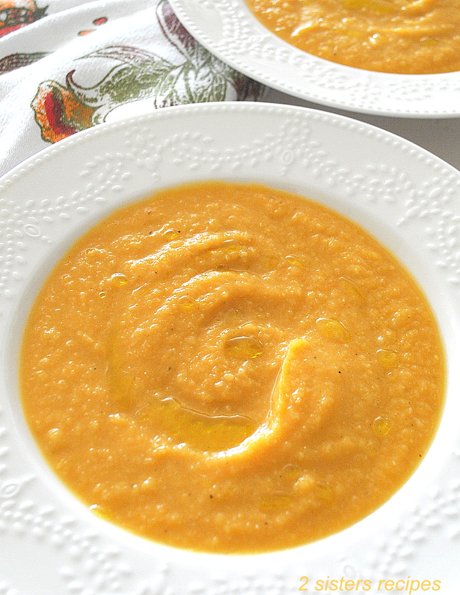 A white plate filled with a thick, creamy sweet potato cauliflower soup.