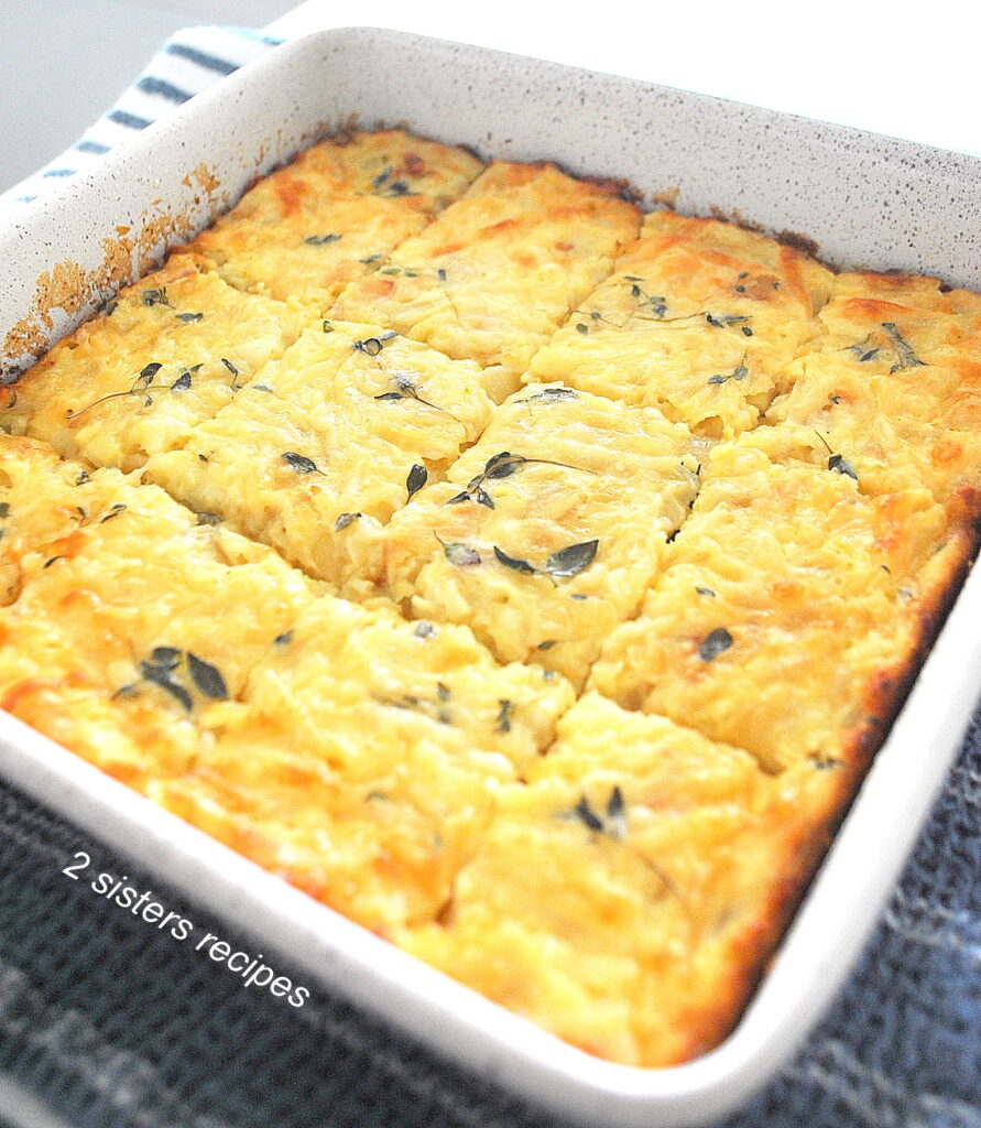 A white square baking pan filled with a baked egg mixture with onions and cheese.