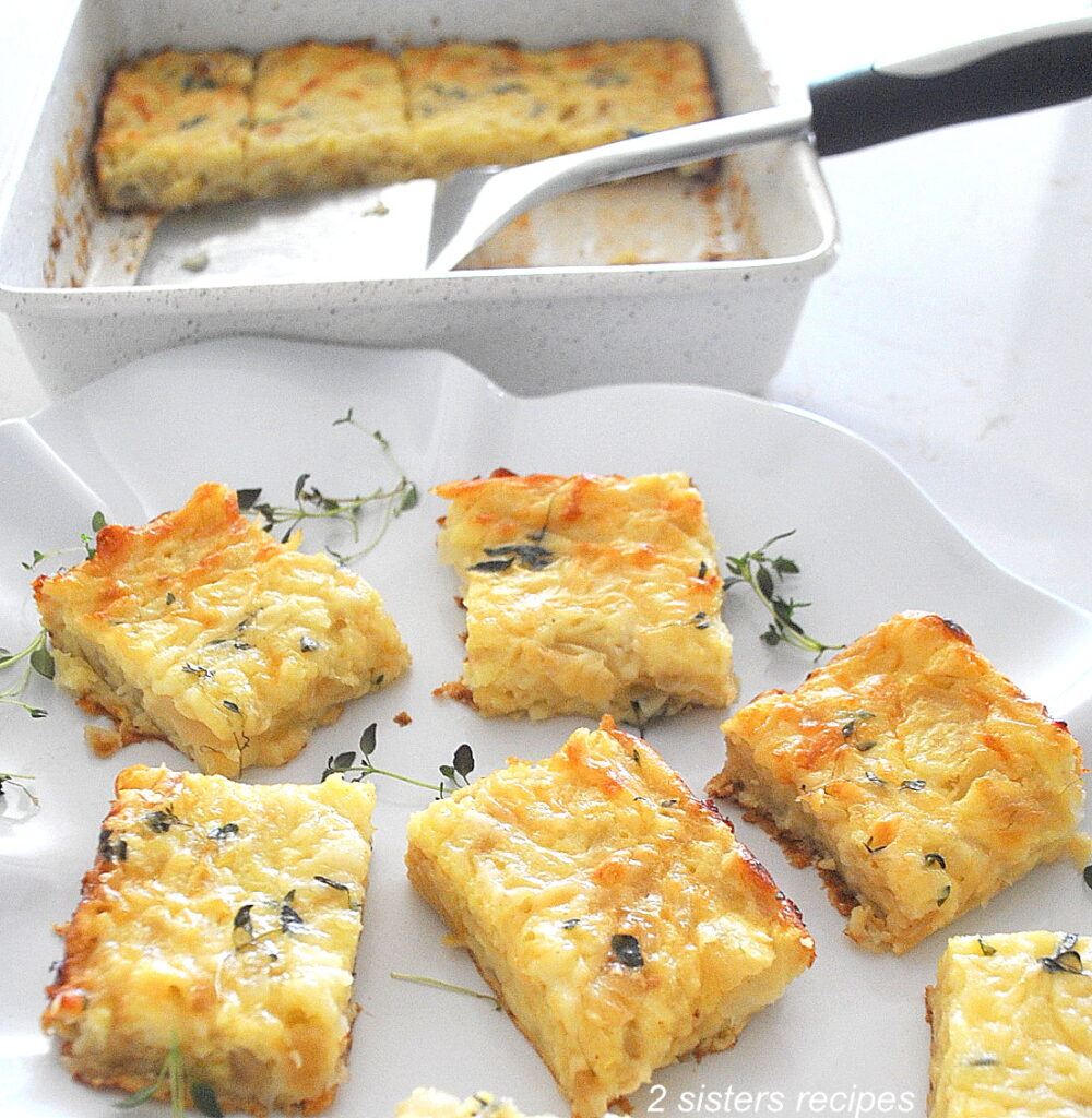 A large white platter filled with baked eggs and onions squares with sprigs of fresh thyme around them.