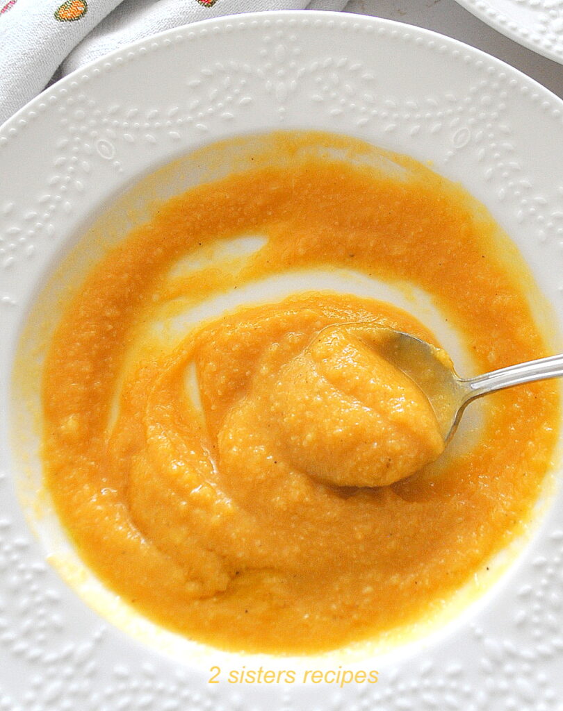 A spoonful of creamy sweet potato cauliflower soup served in a white bowl.