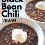 Two white bowls filled with chili and dollop of sour cream on top.