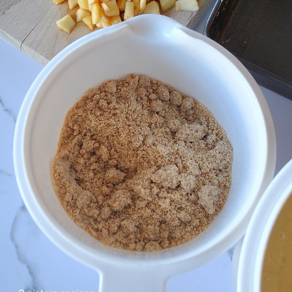 A white mixing bowl filled with a crumble mixture.