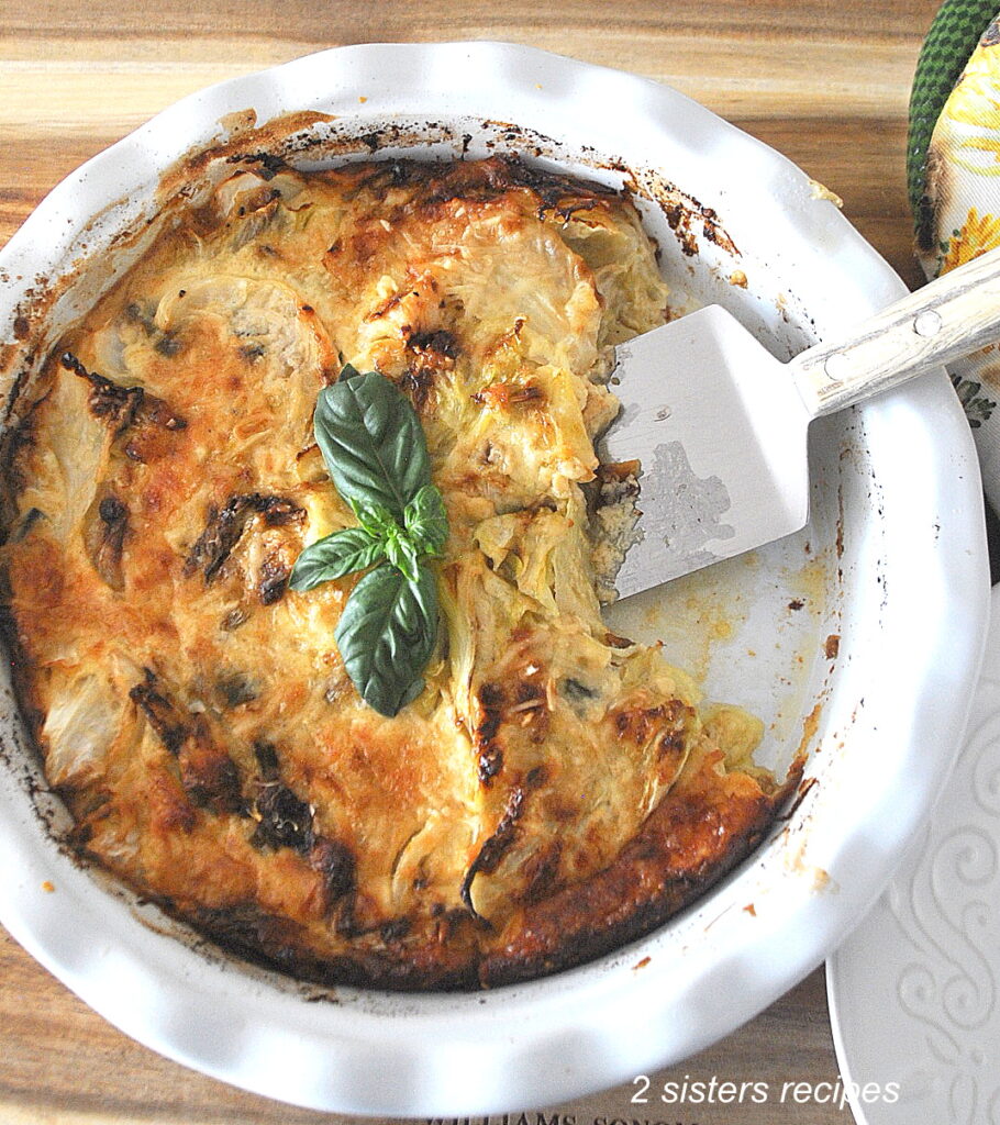 A white pie dish with a cabbage gratin fully baked and a small spatula for serving.