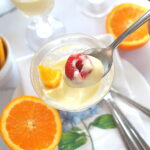 A spoonful of orange posset pudding with a raspberry on top.