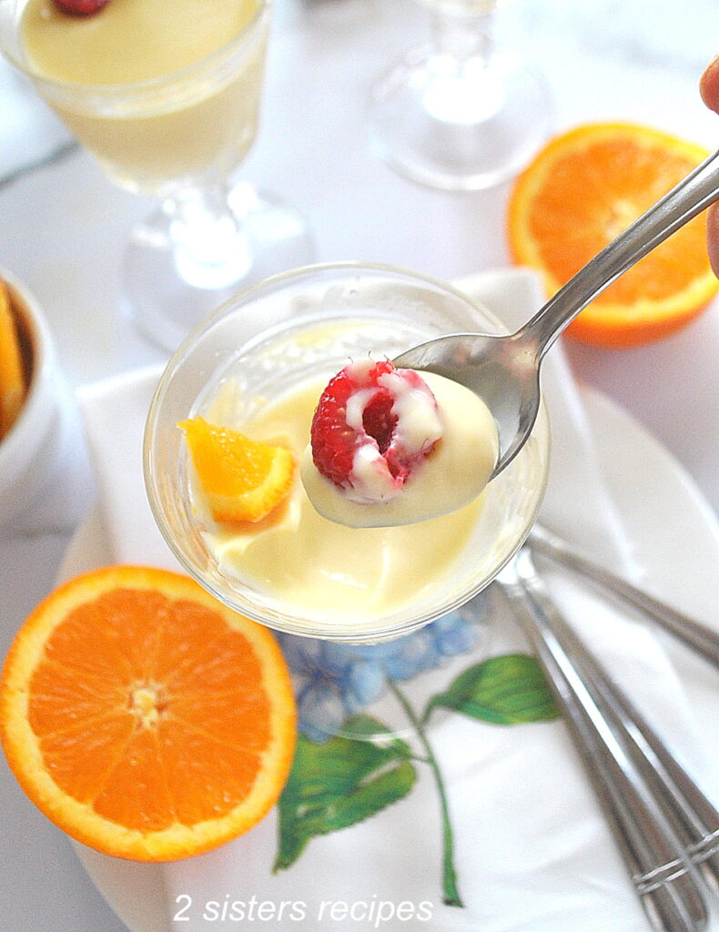 A spoonful of orange posset pudding with a raspberry on top.