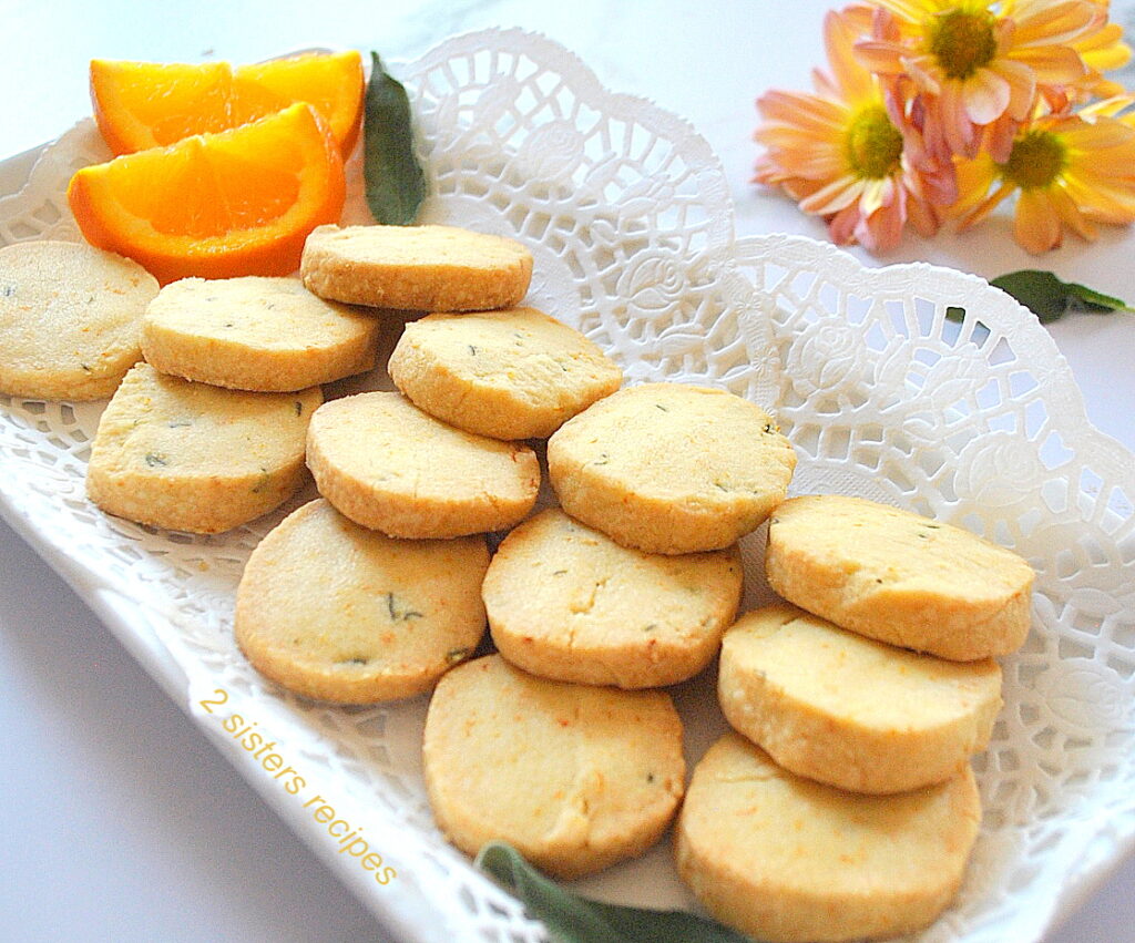A white long platter filled with orange shortbreads with slices of oragne on the side.