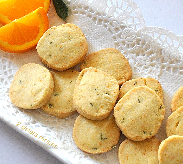 A white platter filled with baked shortbread cookies and 2 orange slices on the side.