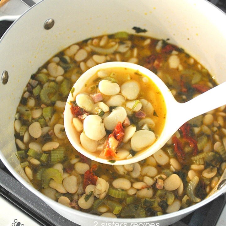 A ladle over a Dutch oven pot filled with a butter beans soup.