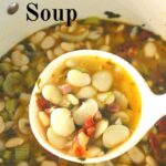 A ladle over a Dutch oven pot filled with a butter beans soup.