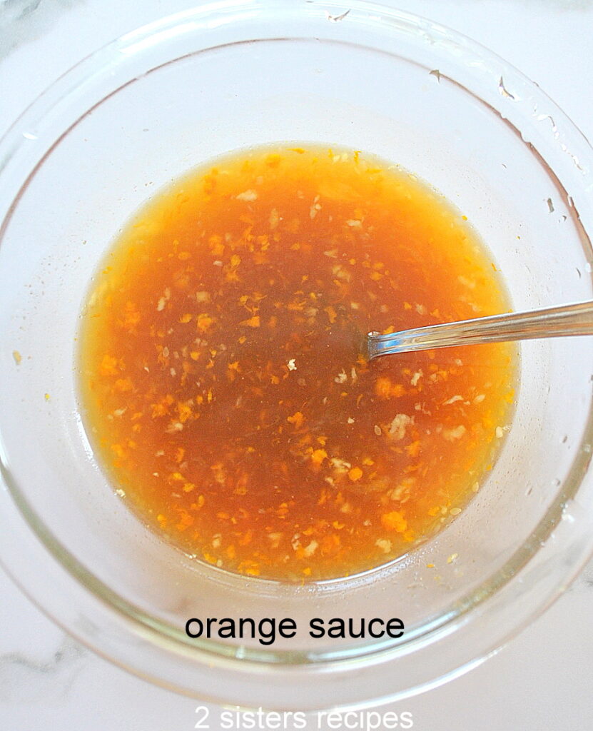 A clrear bowl filled with an orange sauce and a spoon.