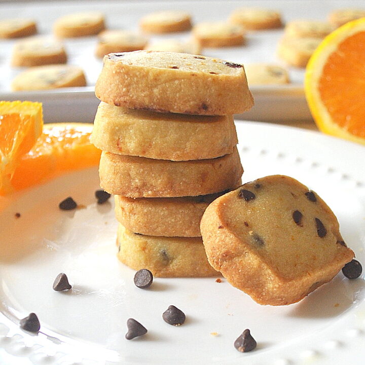 A pile of orange shortbreads with mini chocolate chips on the white plate.