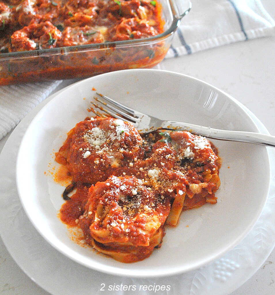 A serving of 3 tagliatella nests pasta smothered in tomato sauce and topped with grated cheese.