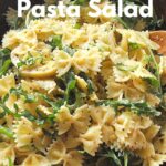 A wooden bowl filled with lemon arugula pasta salad.