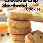 A pile of small square shortbread cookies with mini chocolate chips scattered on a white plate.