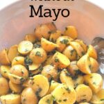 A white salad bowl filled with small cut potatoes salad without mayo.