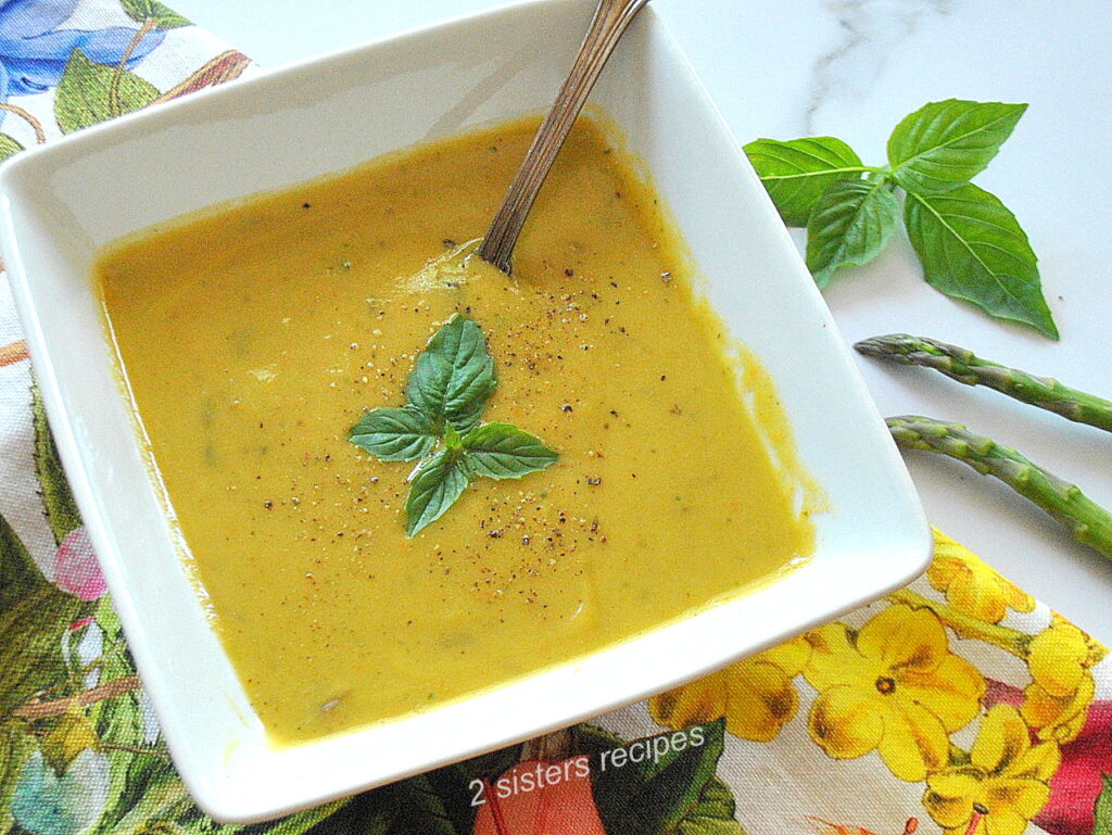 A square bowl filled with asparagus and basil pureed soup.