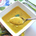 A spponful of creamy green colored soup.